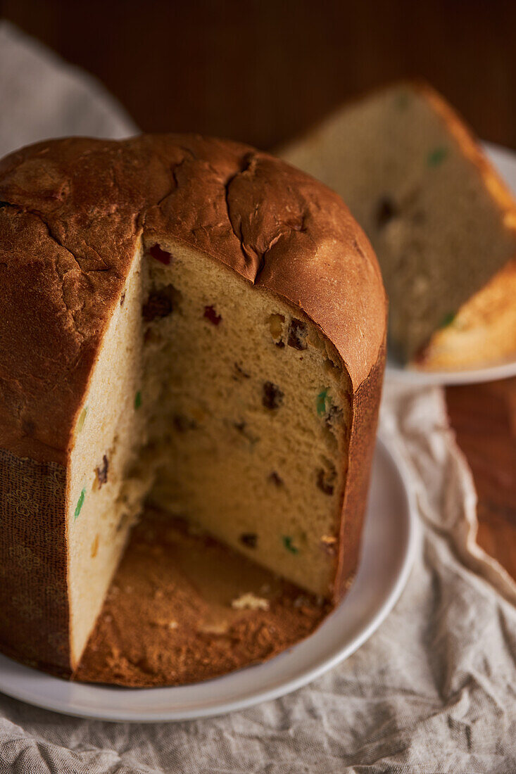 Hoher Winkel von in Scheiben geschnittenem, frisch gebackenem, handwerklich hergestelltem Weihnachts-Panettone-Kuchen auf einem Holztisch