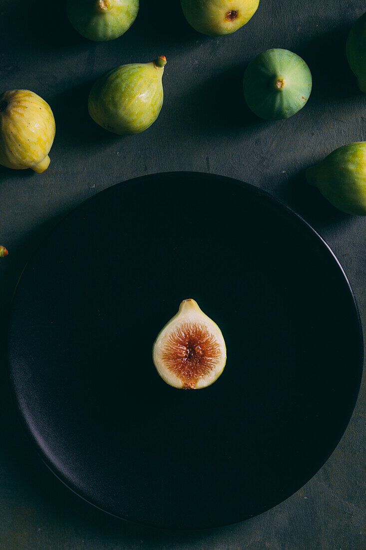Top view of fresh sweet figs arranged on plate on dark background