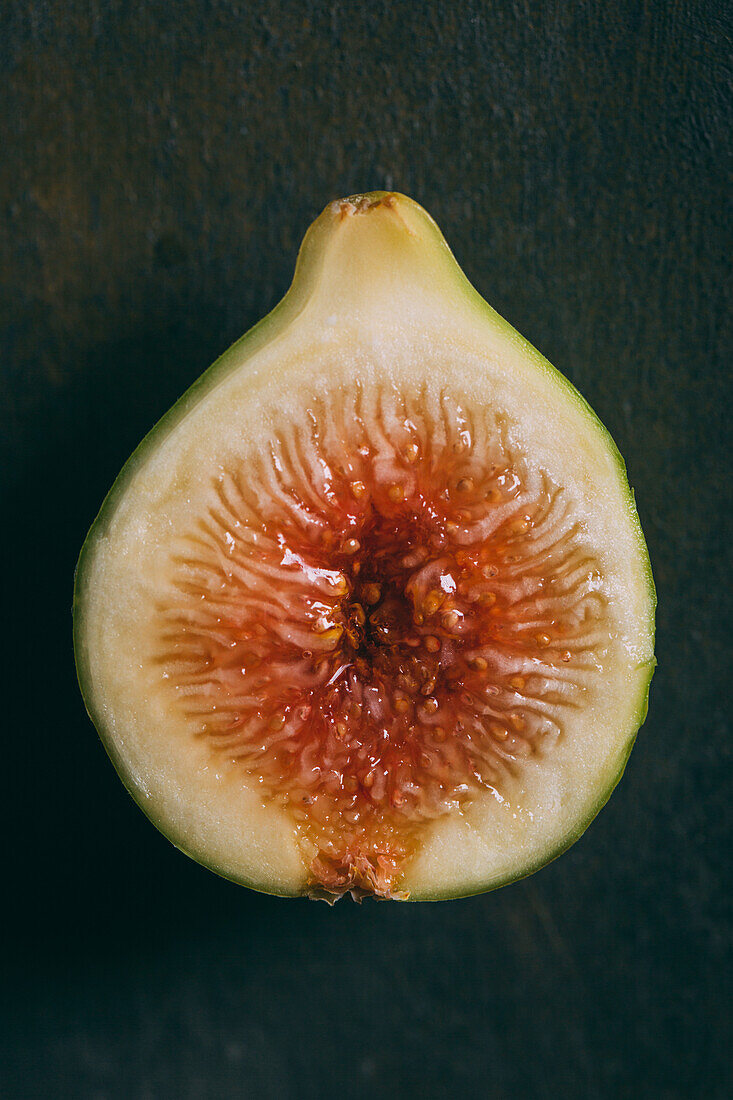 Top view of fresh sweet fig cut in half arranged on dark background