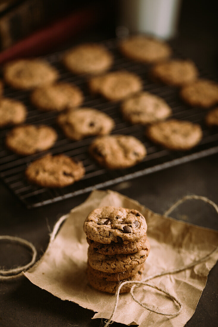 Homemade chocolate chips cookies on cooling rack with a glass of milk