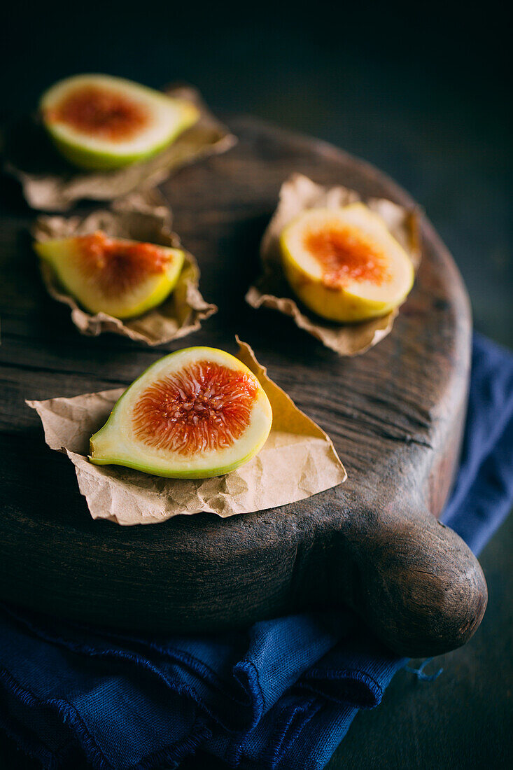 Fresh sweet figs arranged on wooden chopping board on dark background