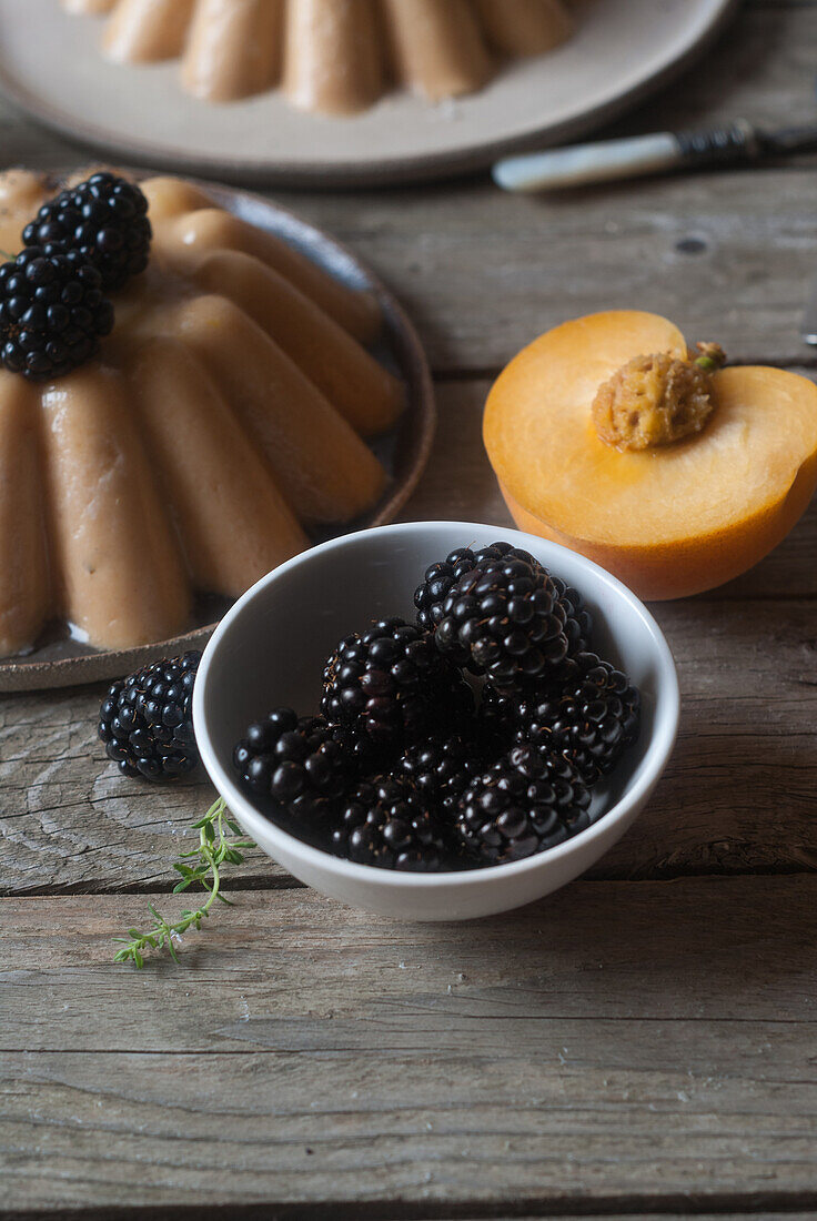 Closeup of served vegan panna cotta with peach and shiny sweet blackberry