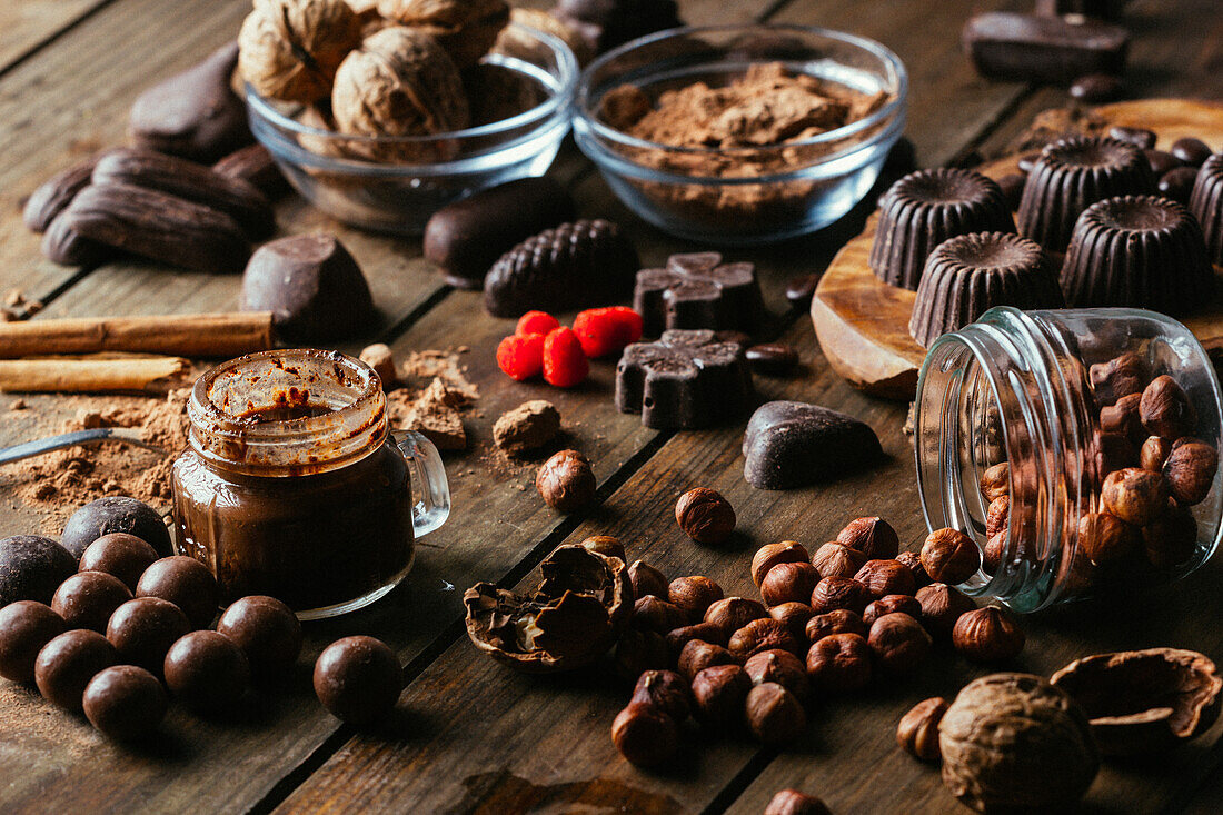 Verschiedene handgemachte Pralinen mit Nüssen auf Holztisch mit Erdnussbutter und Zimtstangen angeordnet
