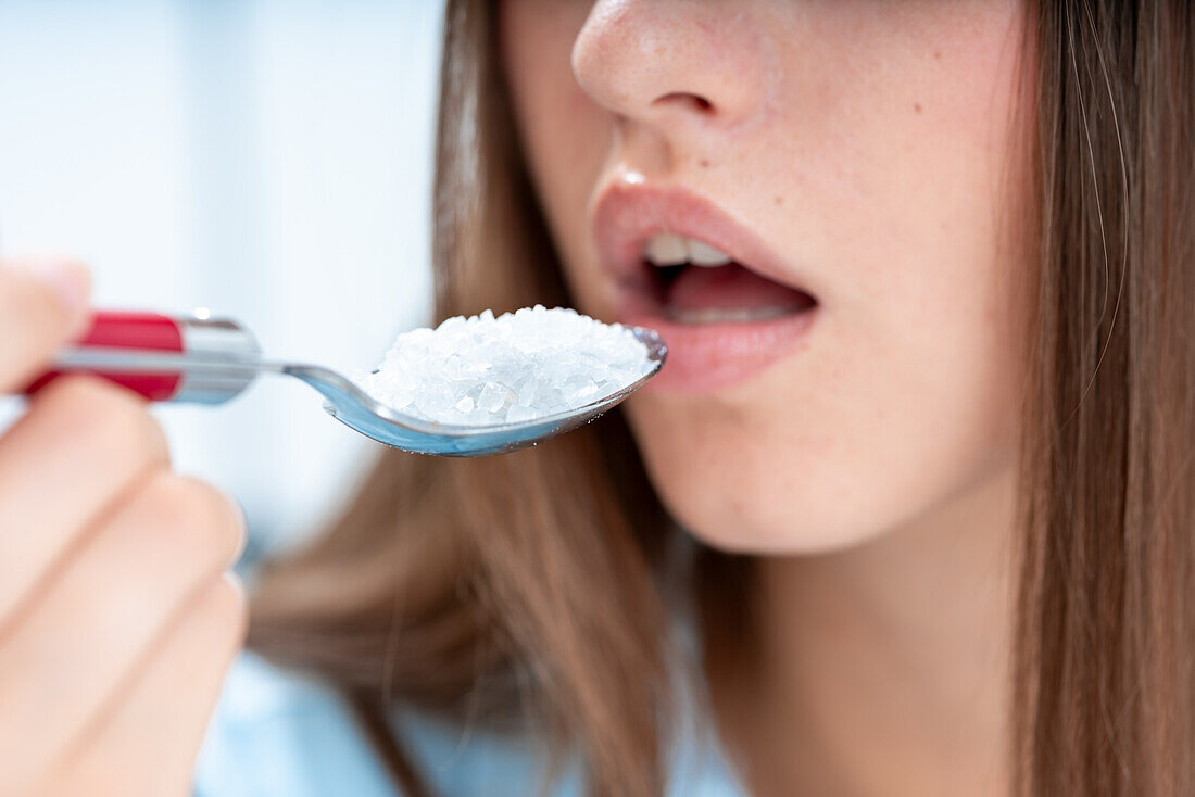 Woman eating a spoon of salt