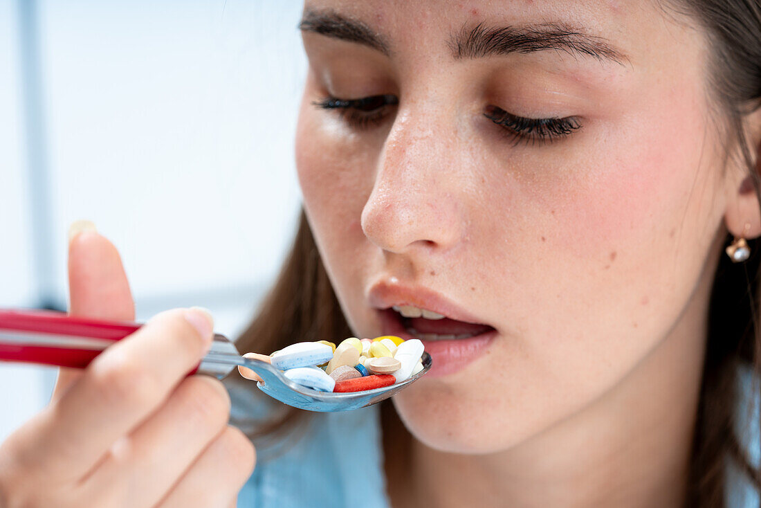 Woman eating spoon filled with pills