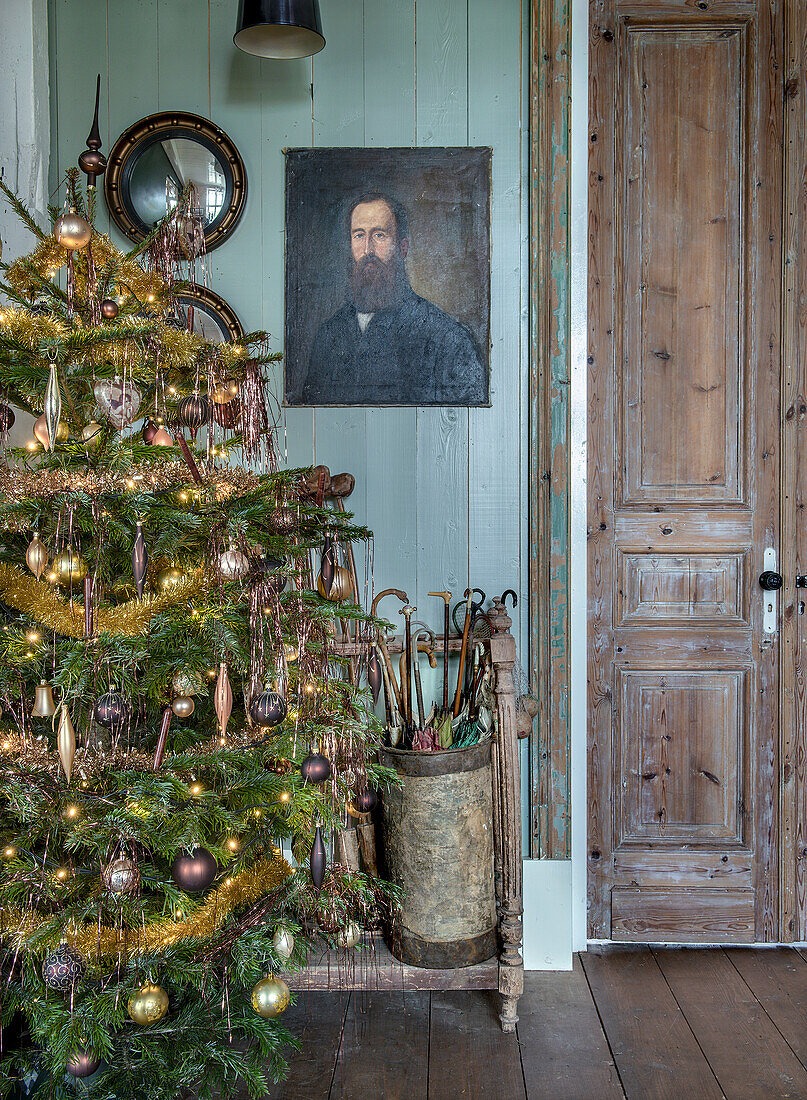 Hallway decorated for Christmas with Christmas tree, antique umbrella stand and oil painting