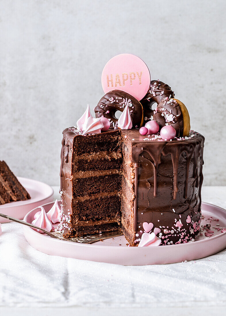 Chocolate Drip Cake mit Donuts und rosa Meringue
