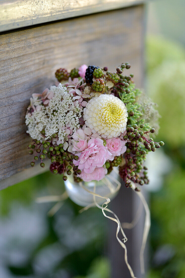 Late summer bouquet with roses, dahlias (Dahlia) and berries hanging on a wooden board