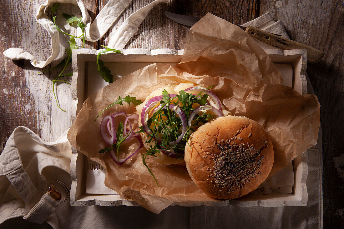 Vegetarischer Burger mit Scamorza, roten Zwiebelringen und Rucola