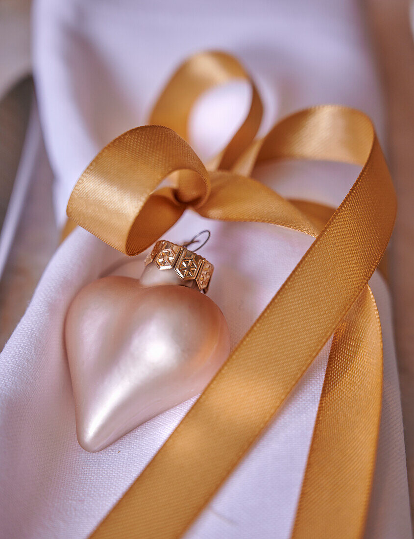 Napkin with heart-shaped tree pendant and gold-coloured ribbon