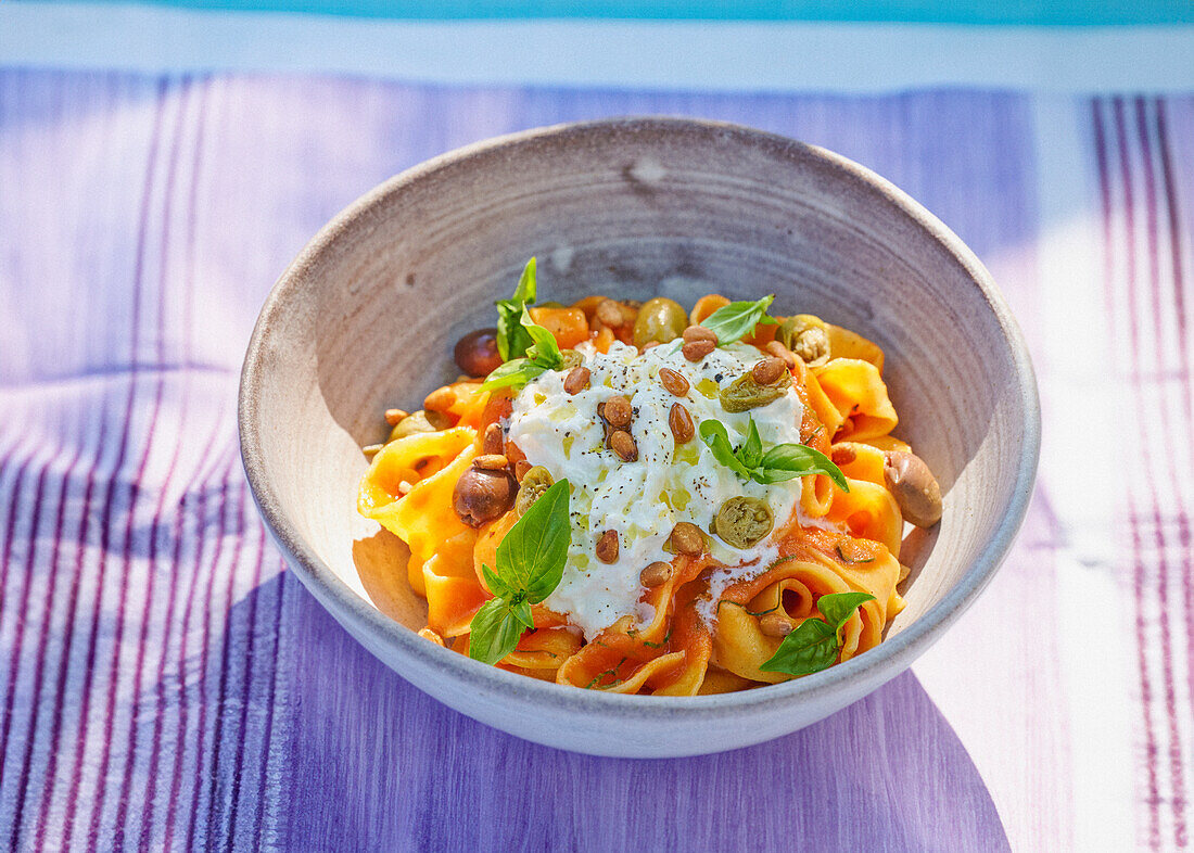 Tagliatelle mit Burrata, Tomaten, Oliven und Pinienkernen