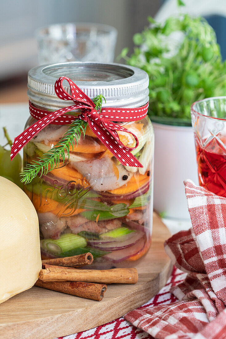 Pickled fish and vegetables in a jar with cinnamon sticks and festive decorations