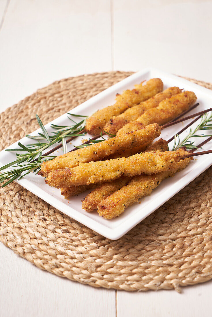 Breaded squid skewers with rosemary sprigs