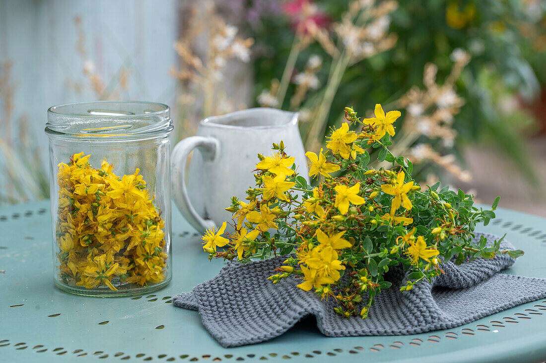 Blumenstrauß aus Johanniskrautblüten (Hypericum Perforatum) und Blüten im Glas auf Gartentisch