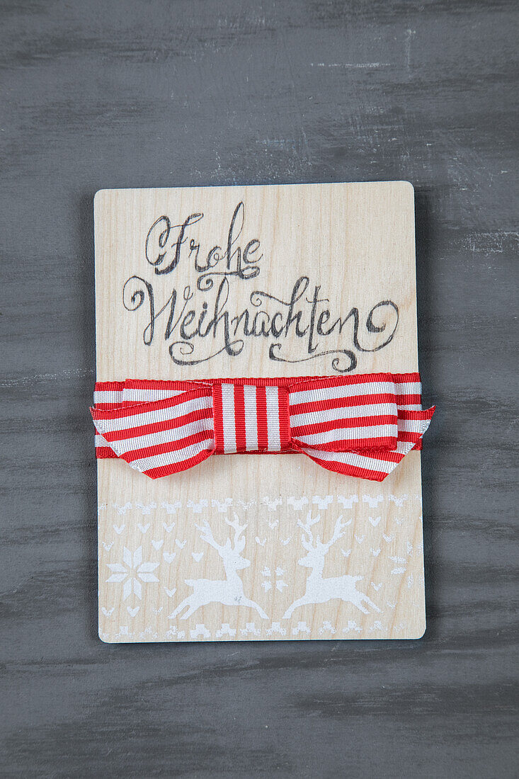 Wooden sign with Merry Christmas lettering and red and white bow