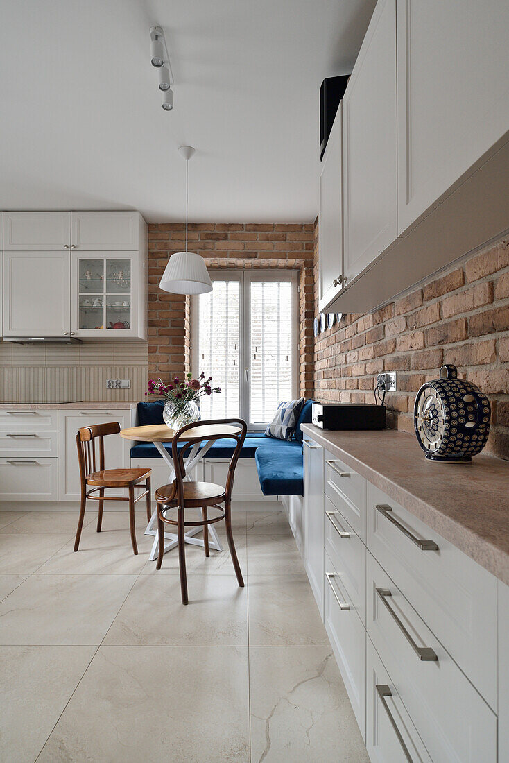 White kitchen with small dining area and brick wall