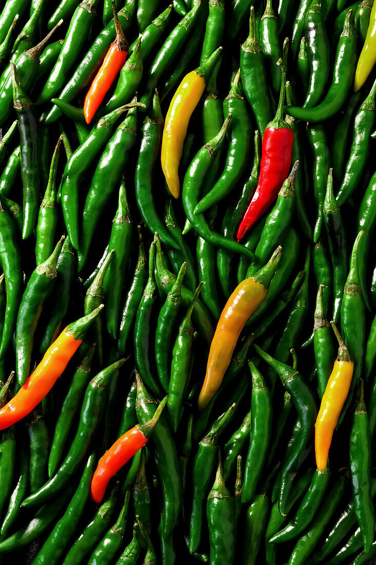 Green and orange birds-eye chillies with a red cayenne pepper