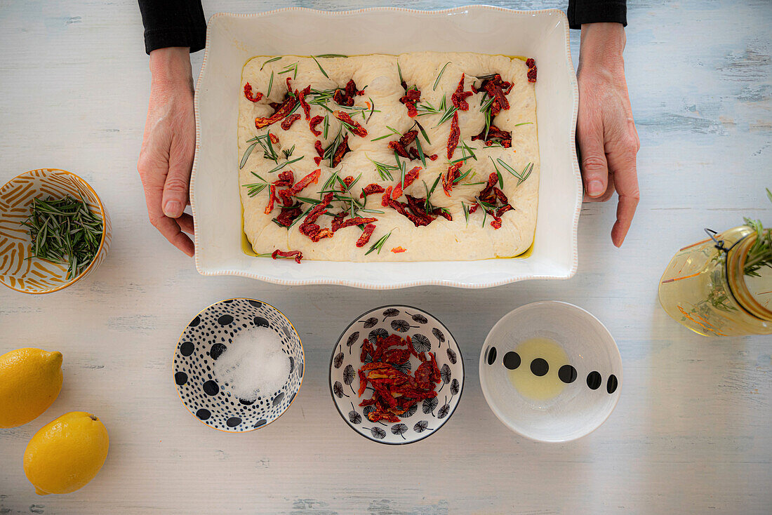 Ungebackenes Focaccia mit getrockneten Tomaten und Kräutern