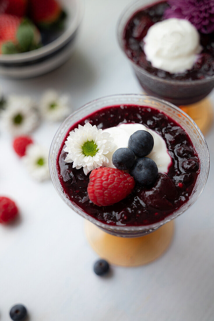 Red fruit jelly with whipped cream and berries