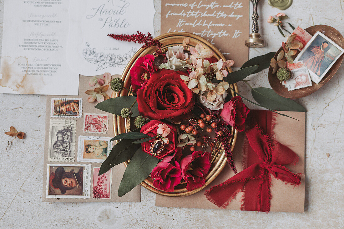 Wedding decor with red roses, invitations and vintage stamps