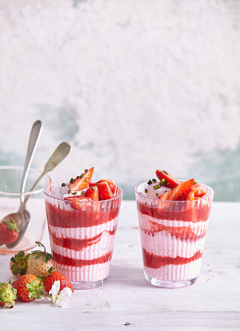 Strawberry cream dessert in a glass with pistachios and lemon zest