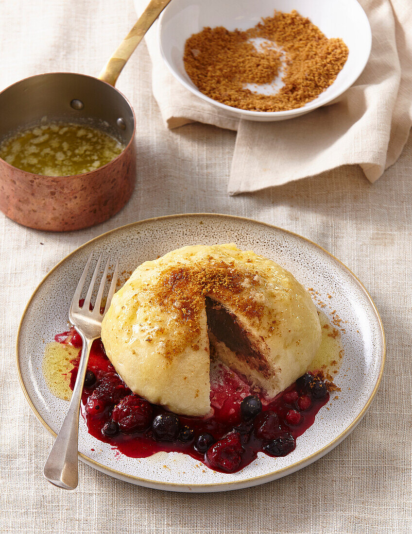 Stuffed yeast dumplings with berry sauce and breadcrumb topping