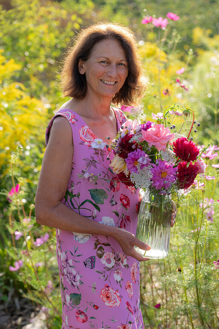 Frau mit Blumenstrauß aus Dahlien (Dahlia), Rosen (Rosa), Herbstanemonen (Anemone Hupehensis) und wilde Möhre