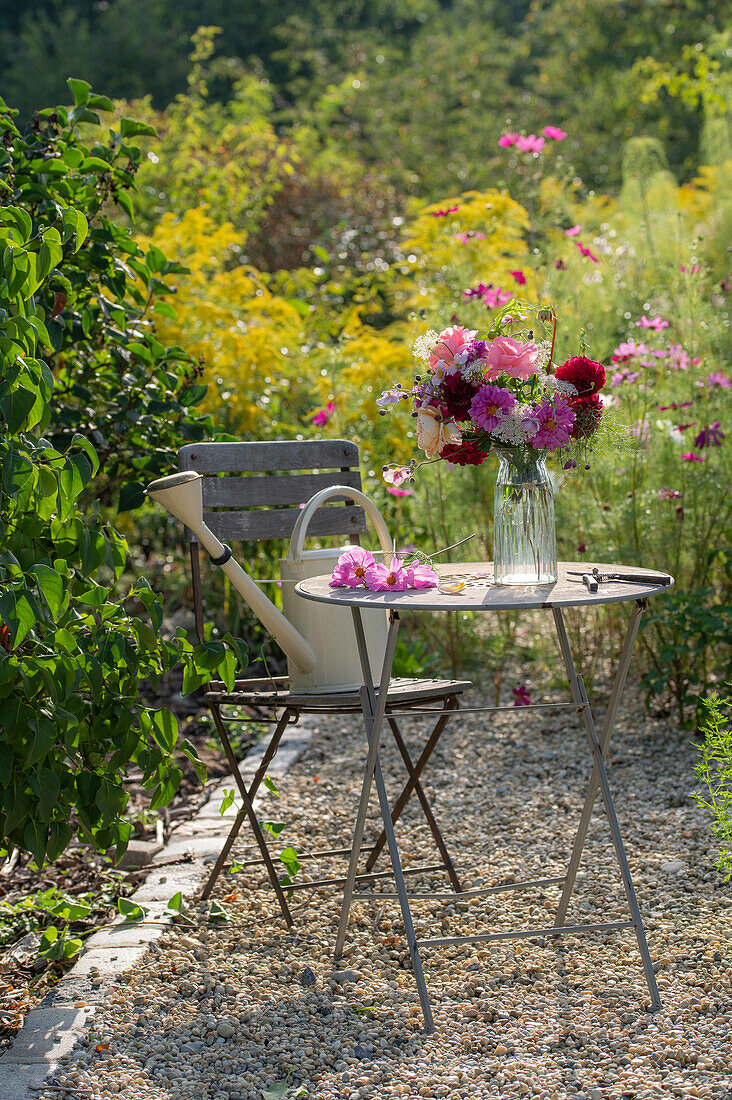 Gartensitzplatz mit Blumenstrauß aus Dahlien (Dahlia), Rosen (Rosa), Herbstanemonen (Anemone Hupehensis) und wilde Möhre