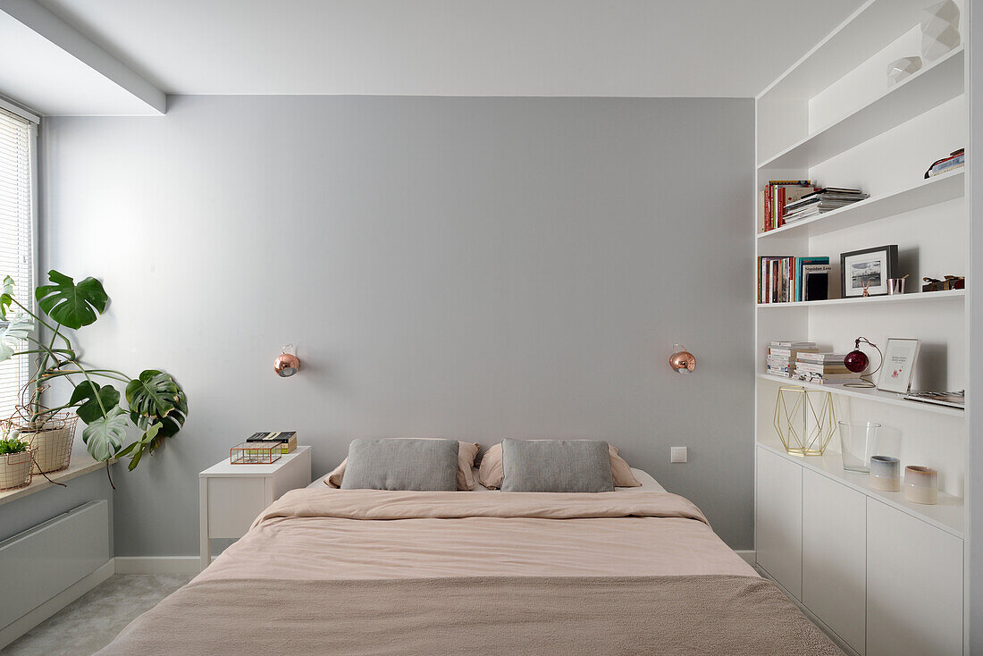 Minimalist bedroom with built-in shelving and copper wall lamps