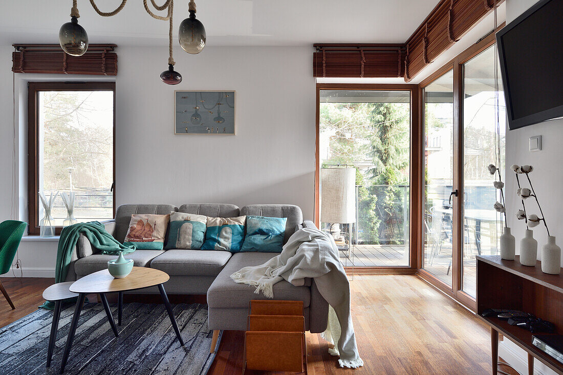 Living room with light grey corner sofa, coffee table and large windows