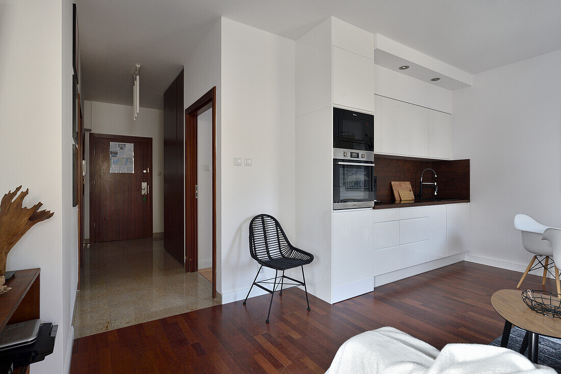 Living area with white kitchen and view of the hallway