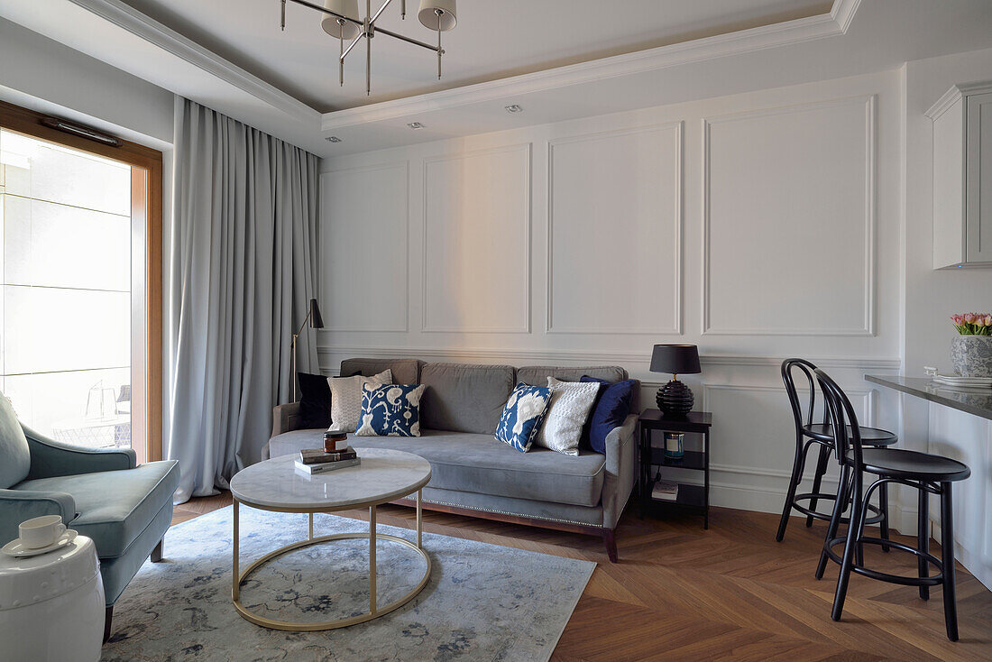 Living room with light grey sofa and white wooden wall paneling