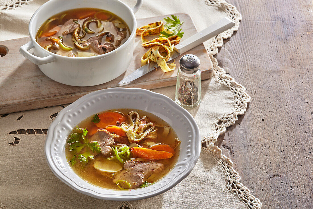 Clear goose broth with vegetables, herbs and pancake strips