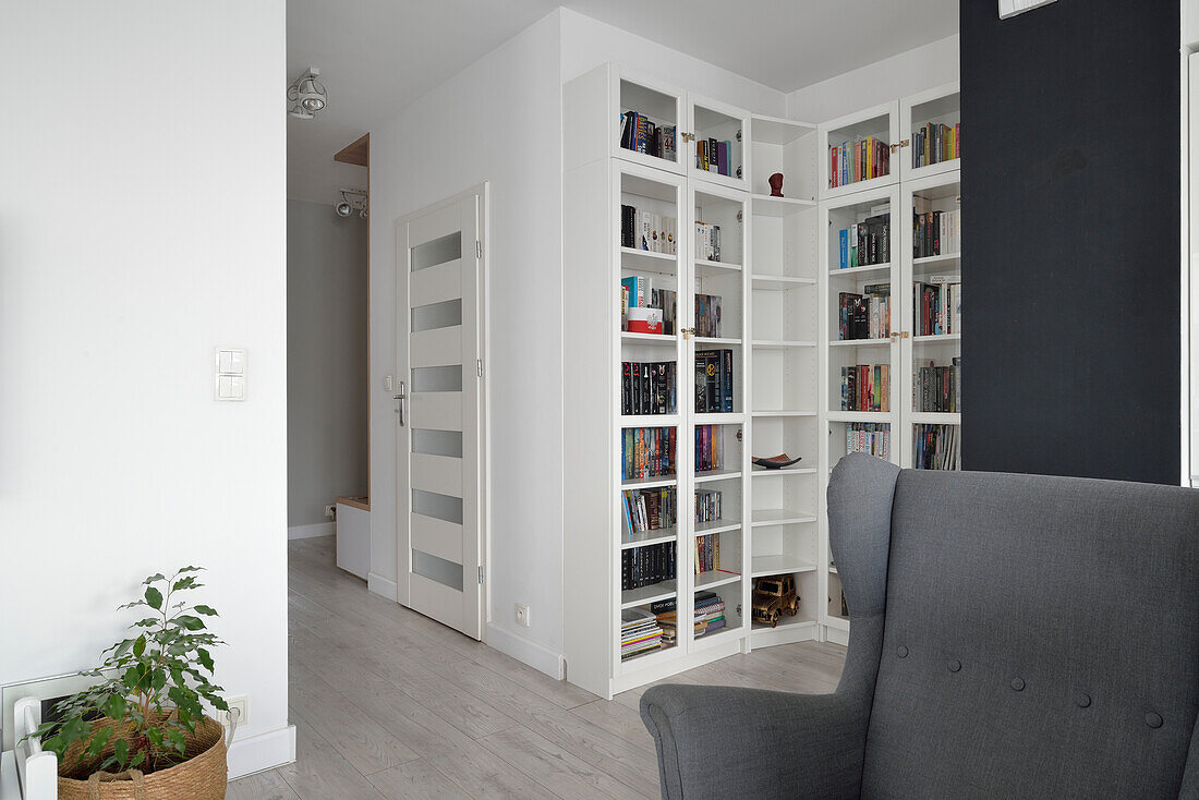 Living room with large bookshelf and grey wing chair