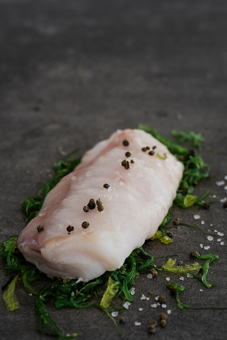 Raw monkfish fillet on wakame salad with peppercorns