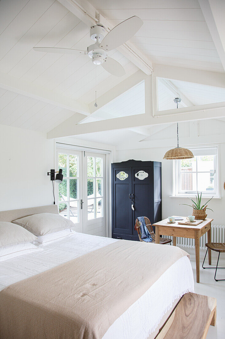 Bedroom with sloping ceiling, wooden table and antique wardrobe in black