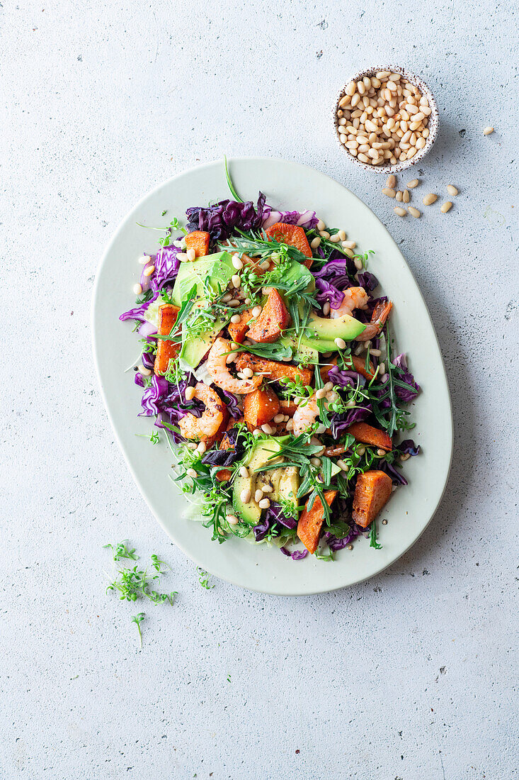 Colourful salad with prawns, avocado, red cabbage, sweet potato and pine nuts
