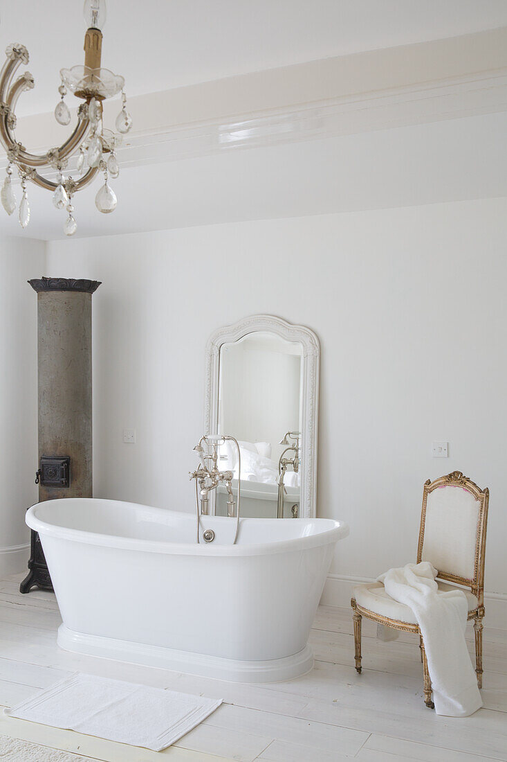 Freestanding bathtub and antique chair in white bathroom