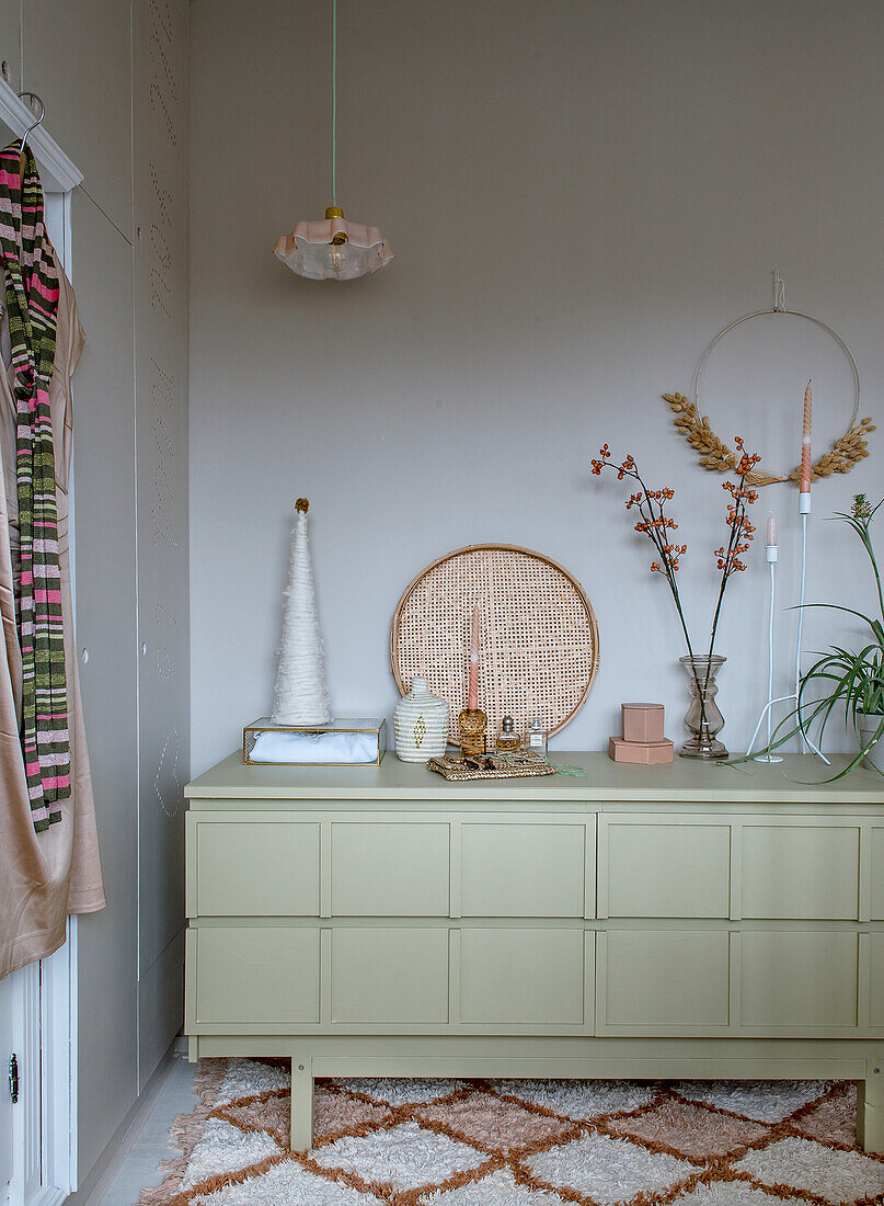 Chest of drawers in pastel green with minimalist Christmas decorations and dried flowers