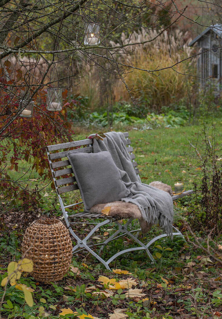 Seat in autumn garden with lanterns hanging in the tree