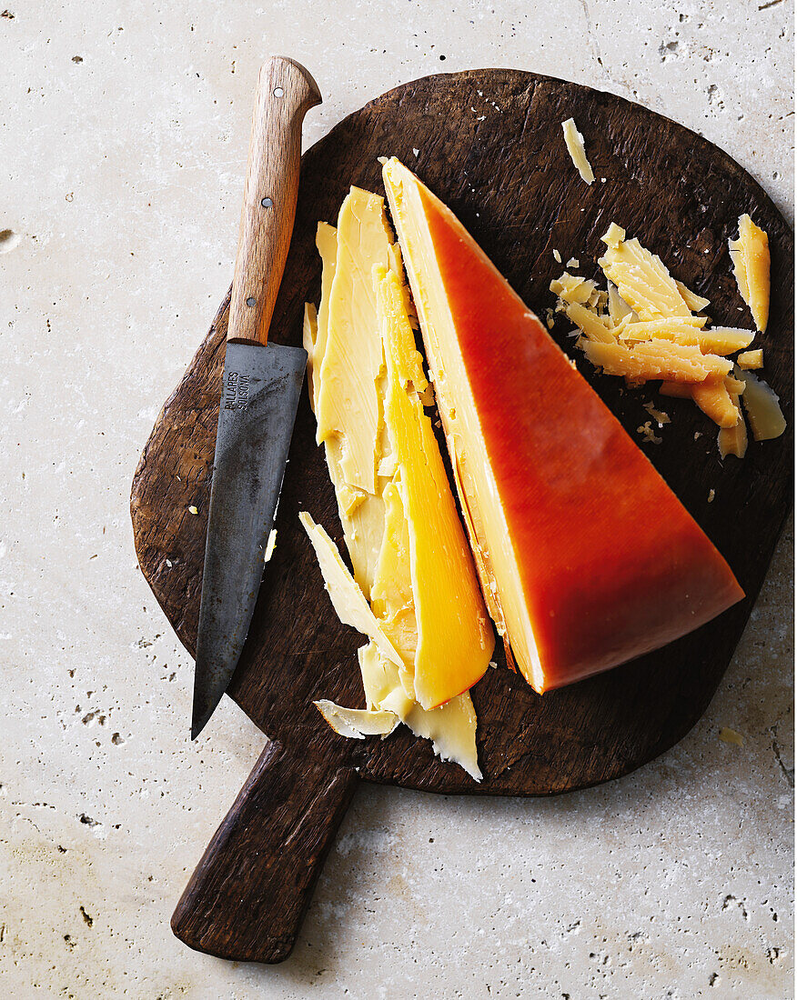 Gouda in one piece with knife on wooden board