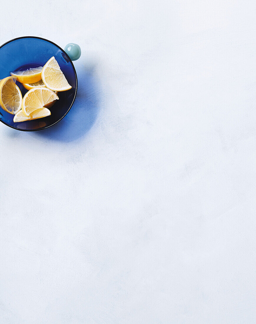 Bowl with lemon wedges on a white background