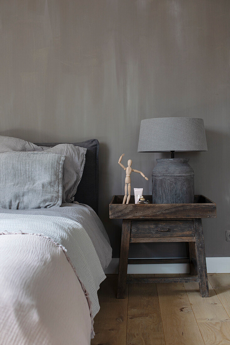 Bedroom in various shades of grey with wooden bedside table