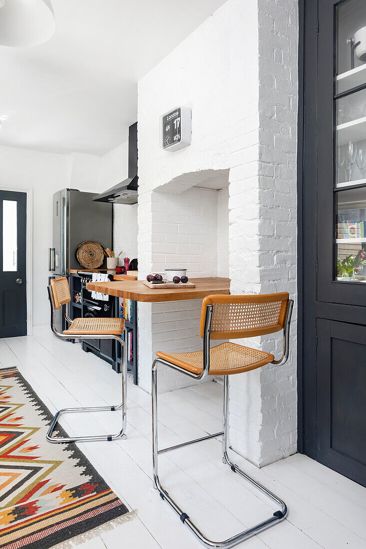 Breakfast bar with bar stools and patterned carpet in kitchen with white wooden floor