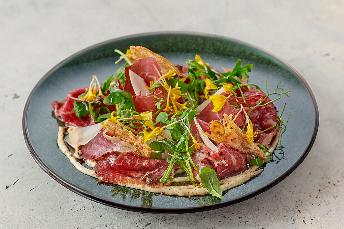 Smoked beef carpaccio with wild herbs, flowers and parmesan crisps
