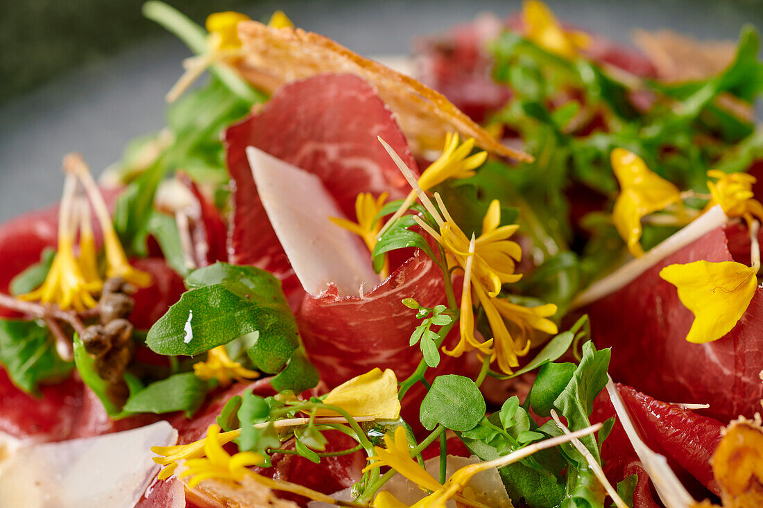 Smoked beef carpaccio with wild herbs, flowers and parmesan crisps