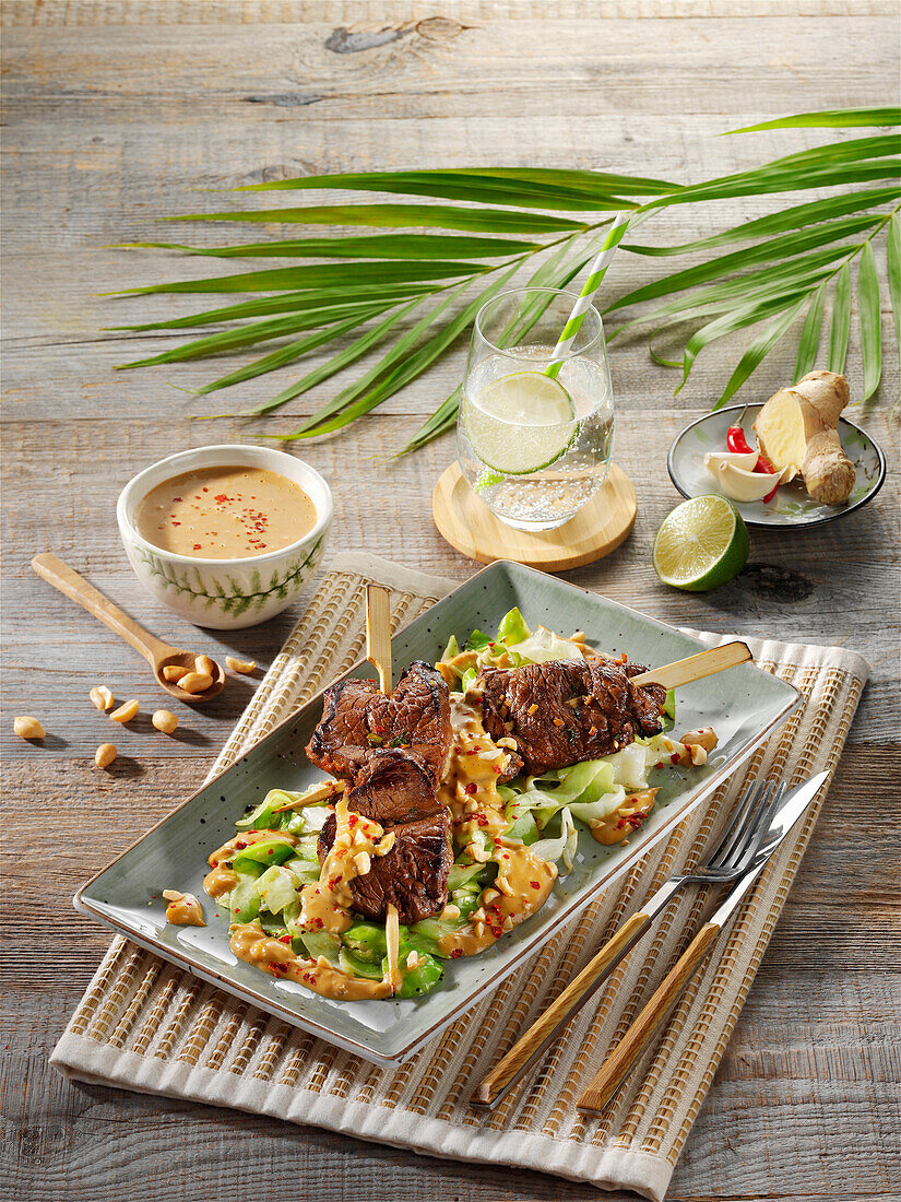 Asian beef saté skewers with peanut sauce on pointed cabbage