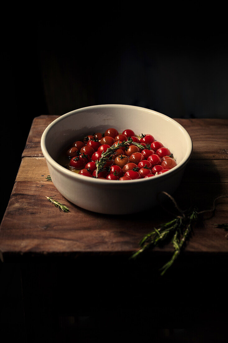 Schüssel mit Kirschtomaten und frischen Kräutern auf Holztisch