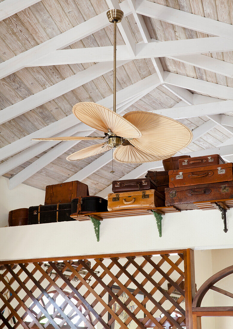 Holzbalkendecke mit Deckenventilator und Vintage-Koffern auf Regal