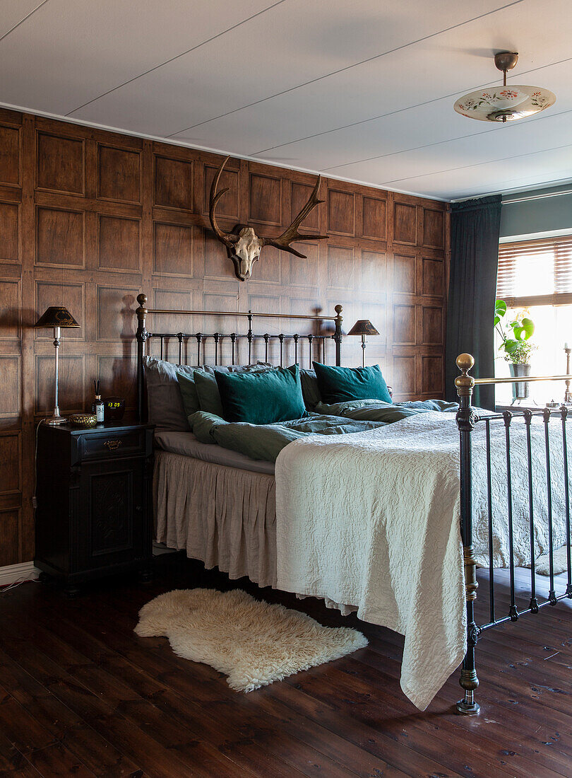 Bedroom with wood paneling, rustic wall decoration and metal bed